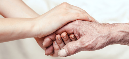 Pflegerin hält die Hand eines Patienten